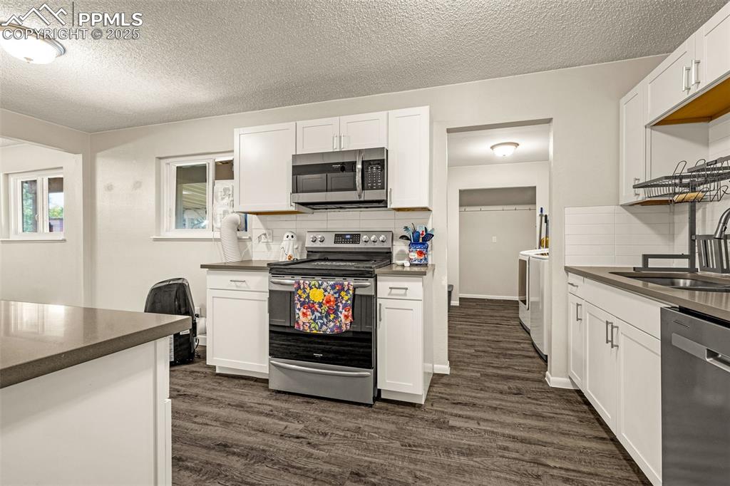 Image 7 of 37: Kitchen featuring stainless steel appliances, dark wood-style flooring, a t