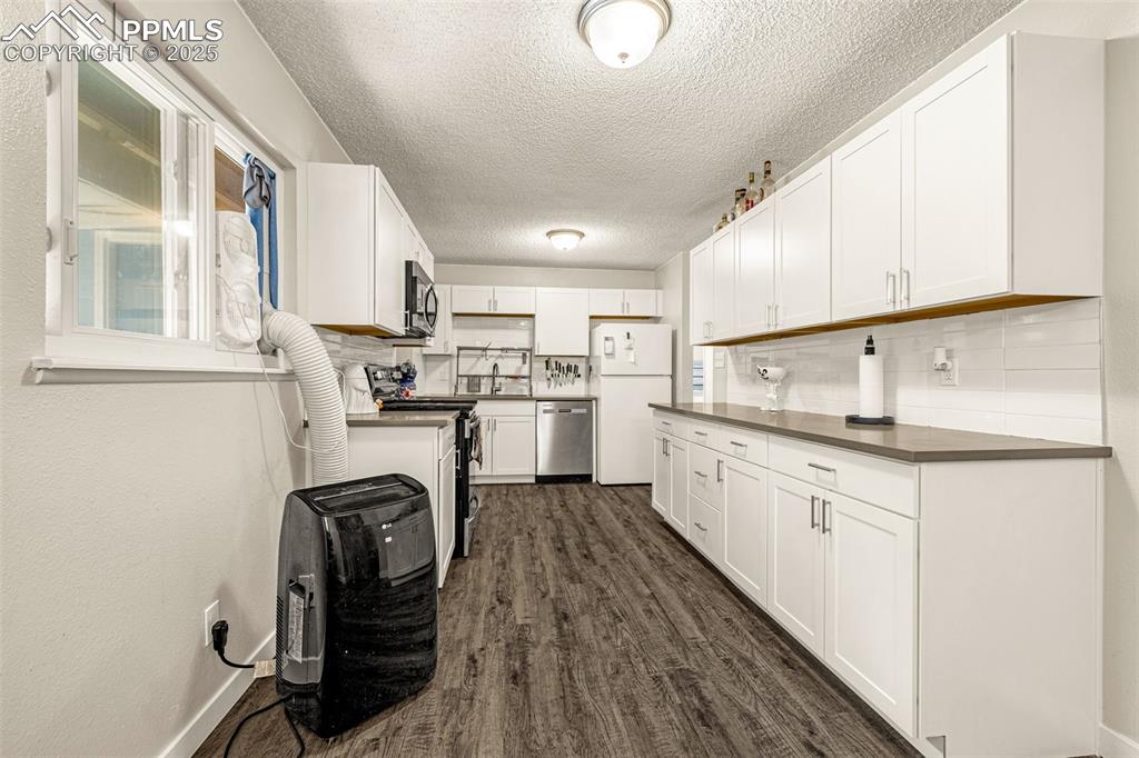 Image 8 of 37: Kitchen featuring white cabinets, a textured ceiling, stainless steel appli