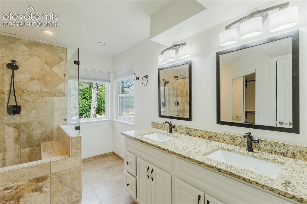 Image 13 of 34: Double vanity and luxurious shower with corner windows for natural light