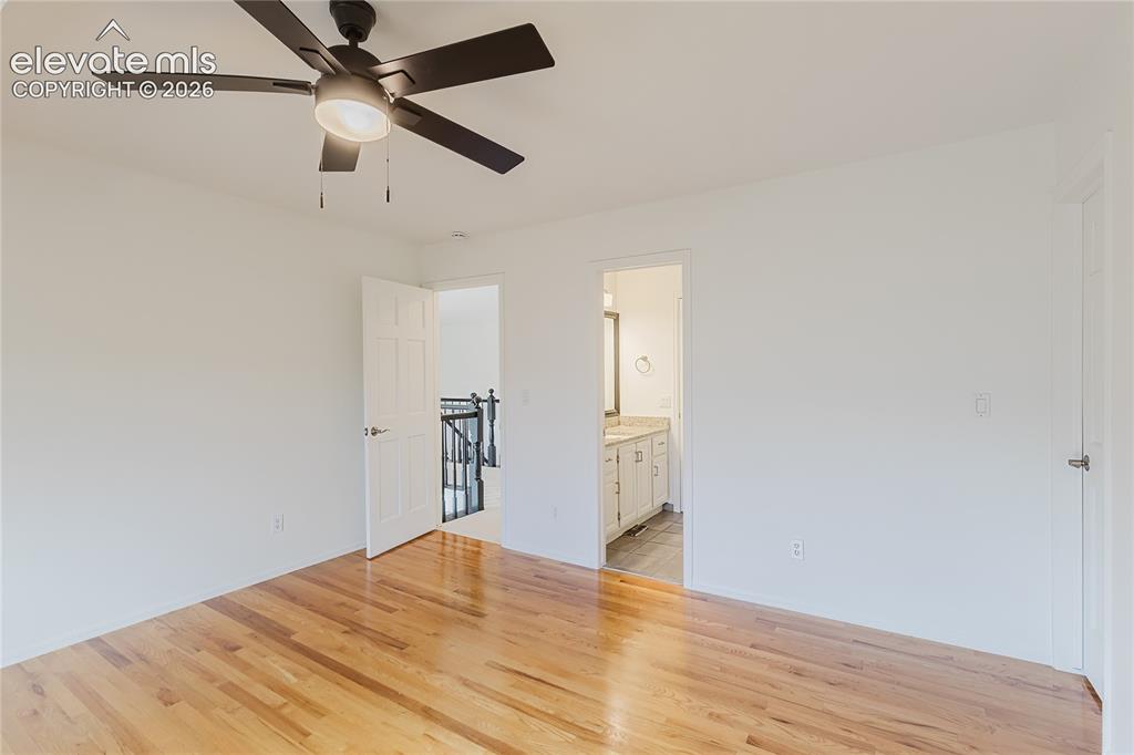 Image 17 of 34: Ceiling fans and wood floors in bedrooms with shared bathroom