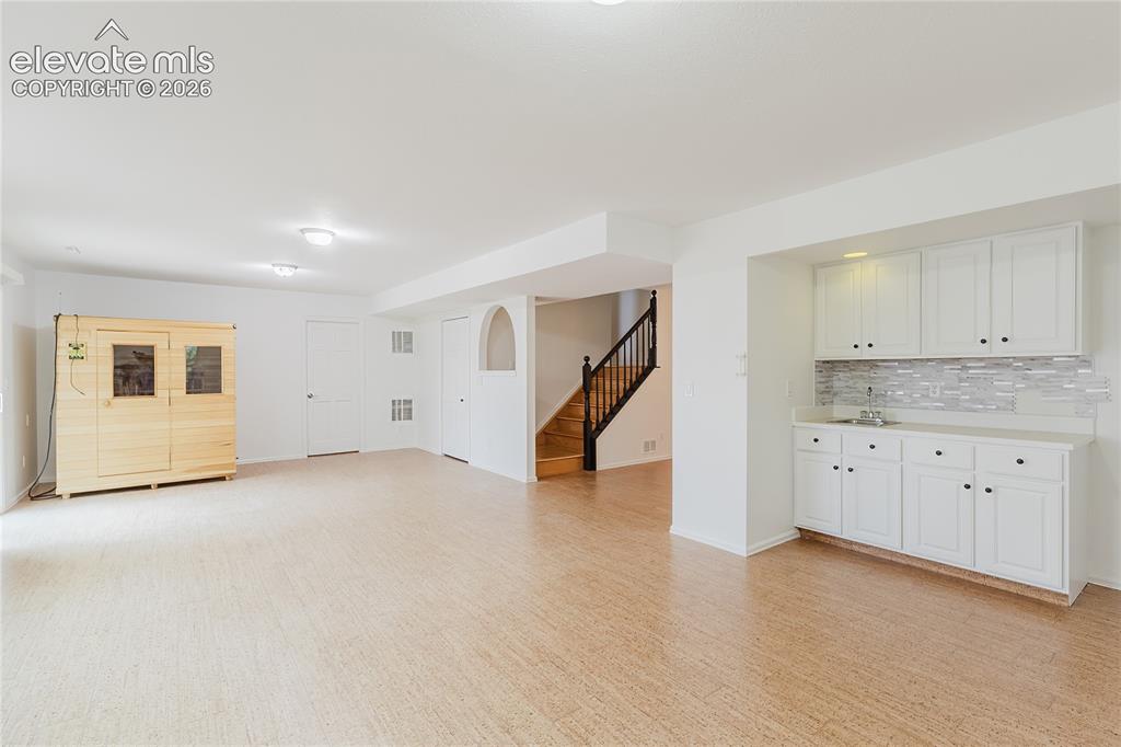 Image 20 of 34: Large basement with wet bar, cork floors, sauna, and walkout to backyard