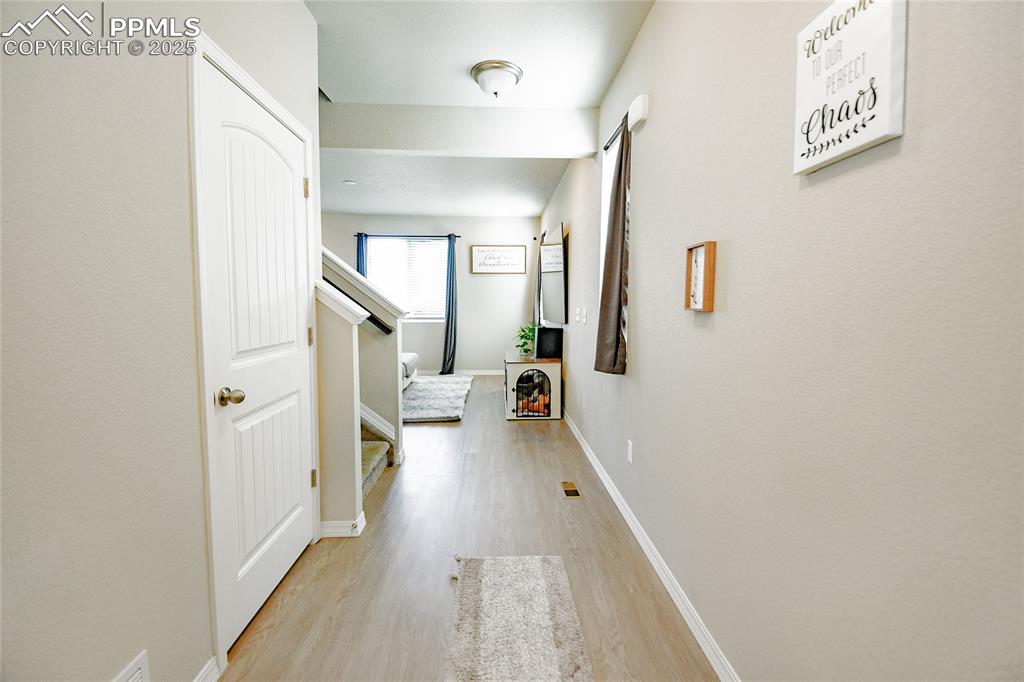 Image 5 of 25: Entry hallway leading to half bath, stairs to upper level and basement, and