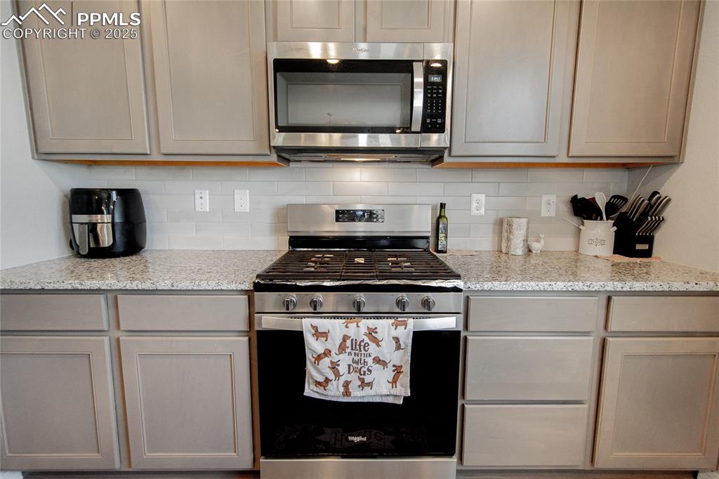 Image 9 of 25: Kitchen with stainless steel appliances, and backsplash