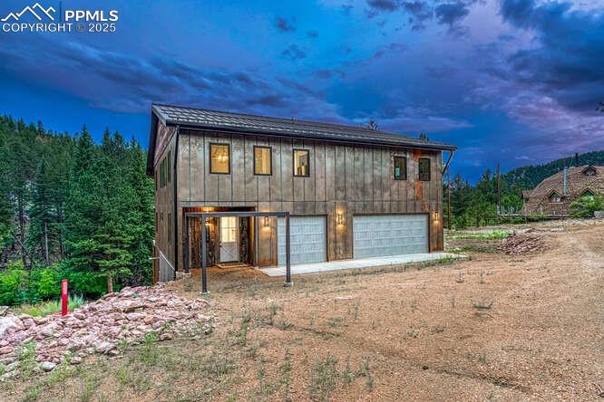 Caption: View of front of house featuring dirt driveway and a garage