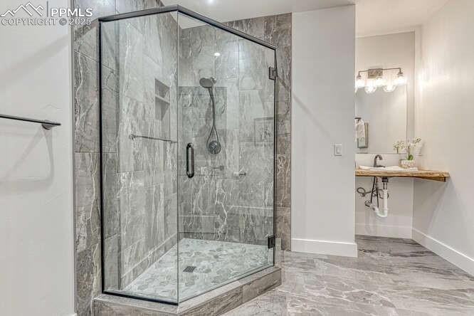 Image 13 of 26: Bathroom featuring marble tiled flooring and a shower stall