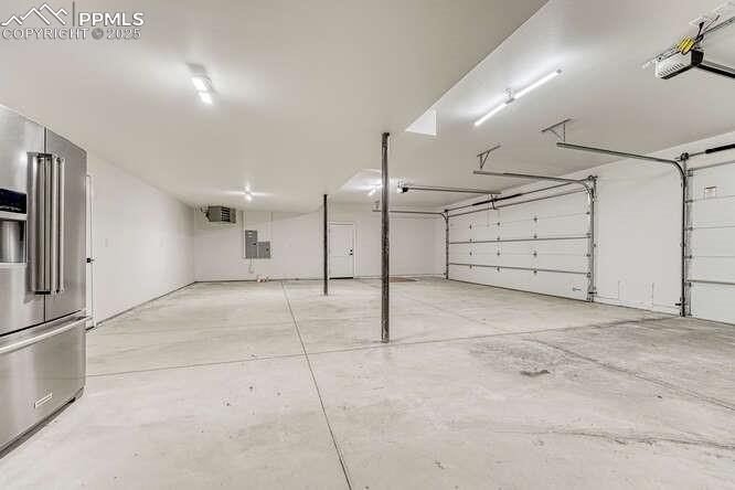 Image 17 of 26: Garage with high end fridge, a garage door opener, and a heating unit