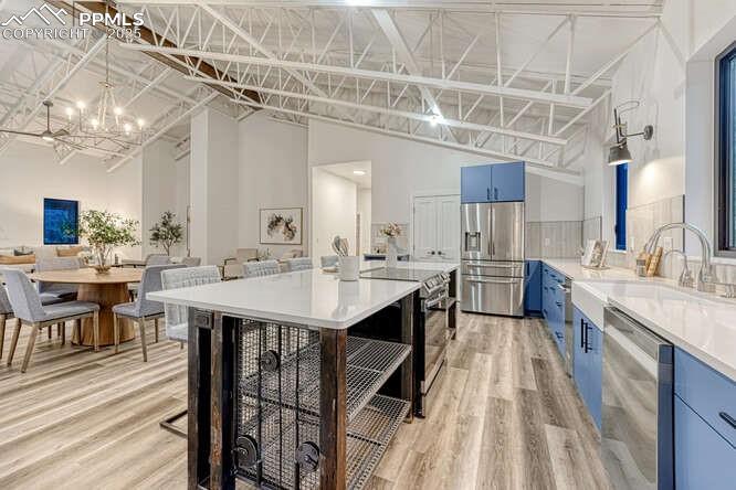 Image 21 of 26: Kitchen with blue cabinetry, a chandelier, stainless steel appliances, ligh