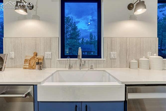 Image 22 of 26: Kitchen with stainless steel dishwasher, blue cabinetry, and light countert