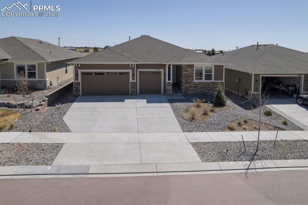 Caption: Single story home featuring concrete driveway, an attached garage, stone siding, and a shingled roof