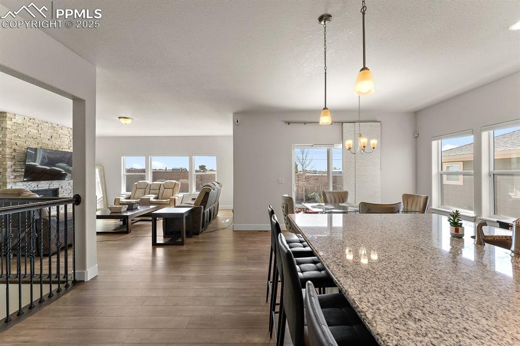 Image 12 of 46: Kitchen featuring a kitchen breakfast bar, a notable chandelier, light ston