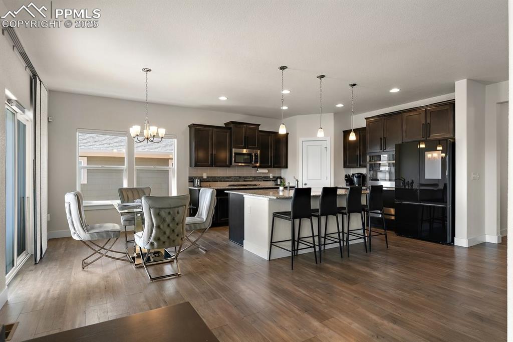 Image 16 of 46: Kitchen with dark wood-style flooring, dark brown cabinetry, stainless stee
