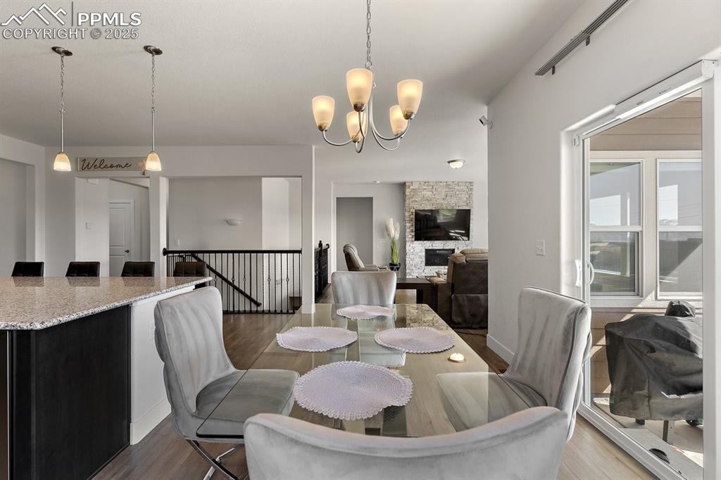 Image 17 of 46: Dining space featuring a stone fireplace, baseboards, a notable chandelier,