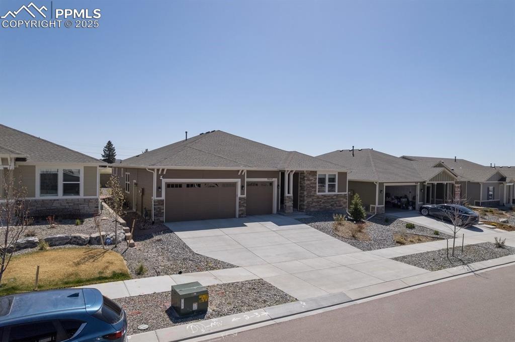 Image 2 of 46: Ranch-style home featuring a garage, driveway, stone siding, and a shingled