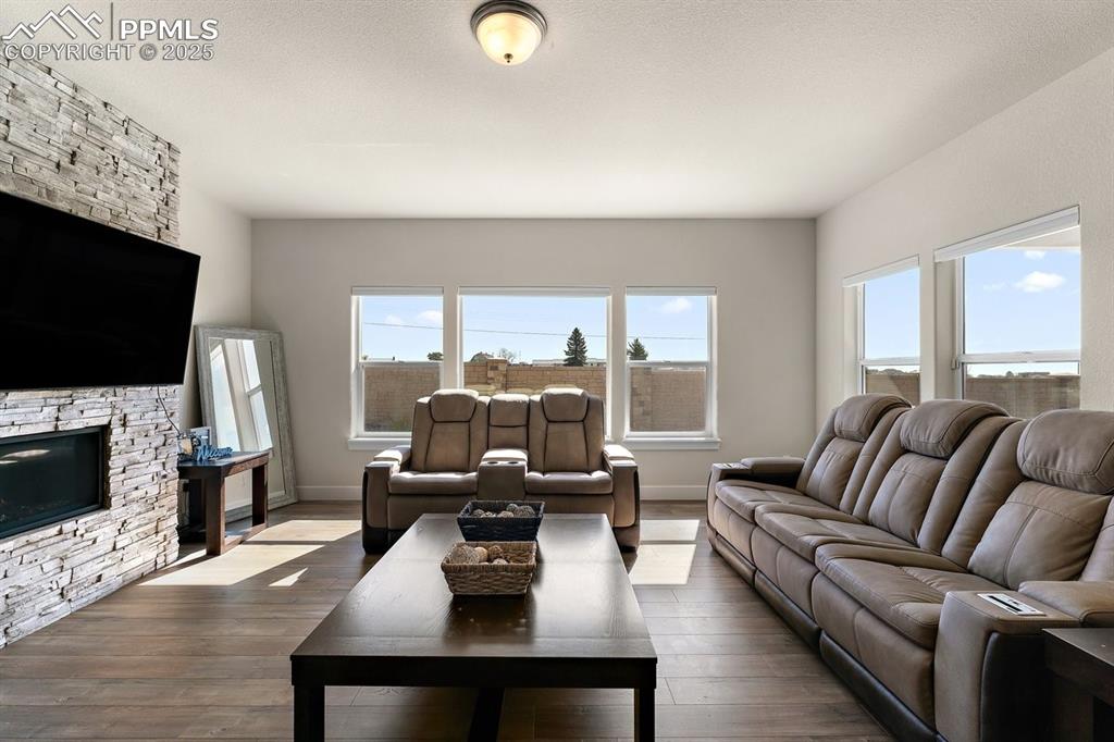 Image 22 of 46: Living area with baseboards, a stone fireplace, and hardwood / wood-style f
