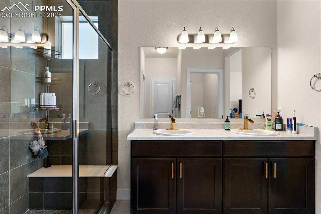 Image 30 of 46: Full bathroom featuring a sink, double vanity, and a stall shower