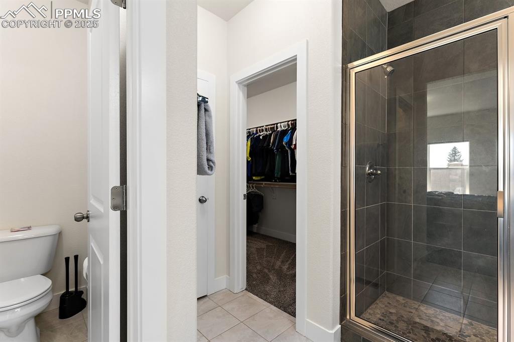 Image 31 of 46: Bathroom with a spacious closet, tile patterned flooring, a shower stall, a