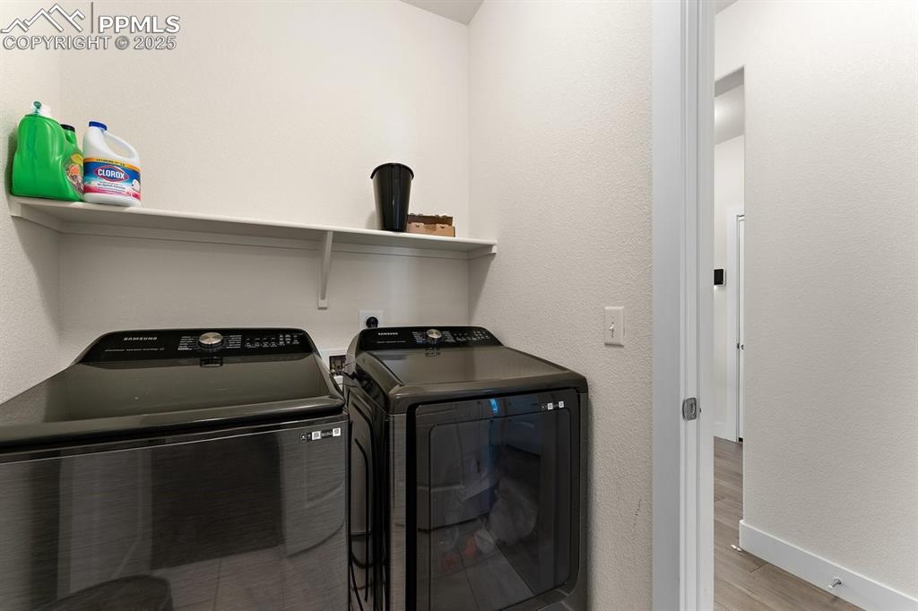 Image 34 of 46: Clothes washing area featuring baseboards, wood finished floors, laundry ar