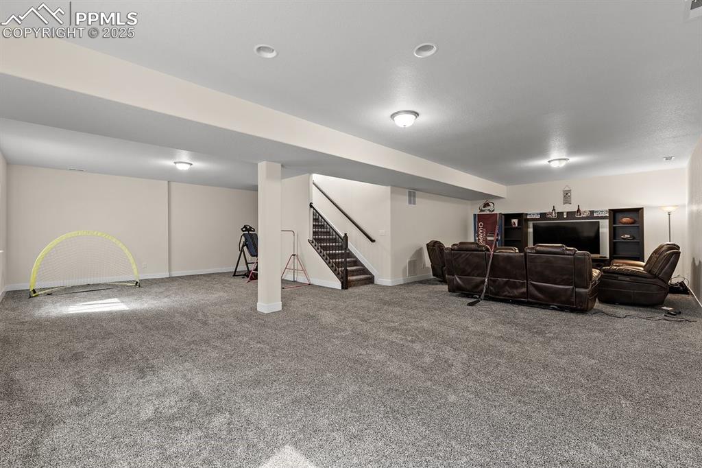 Image 38 of 46: Living area with baseboards, carpet floors, and stairs