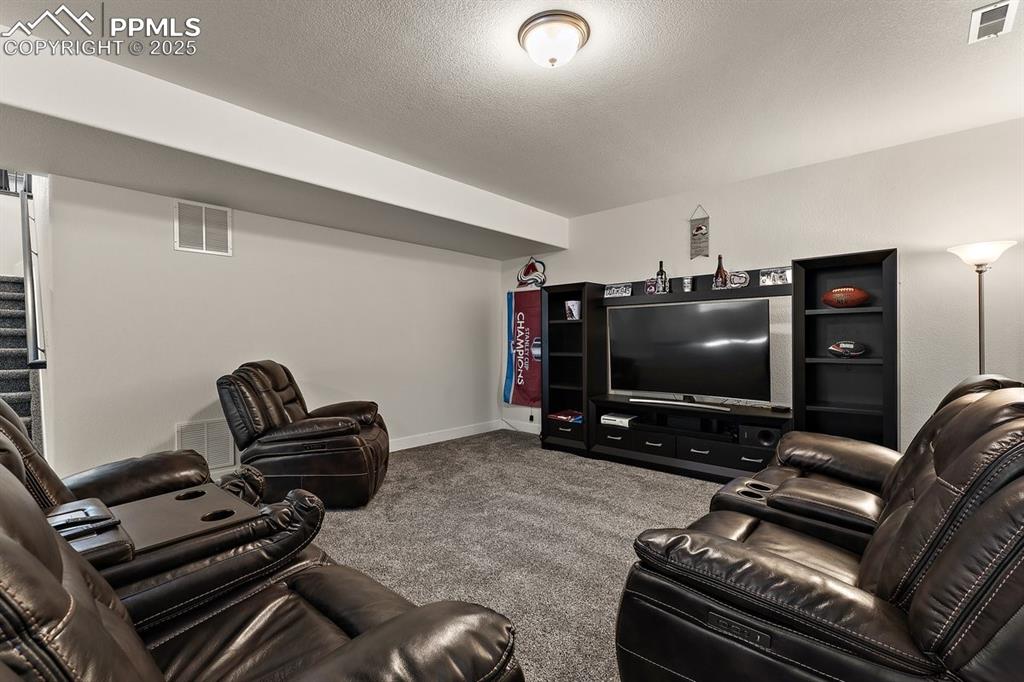 Image 39 of 46: Living room featuring a textured ceiling, carpet floors, visible vents, and