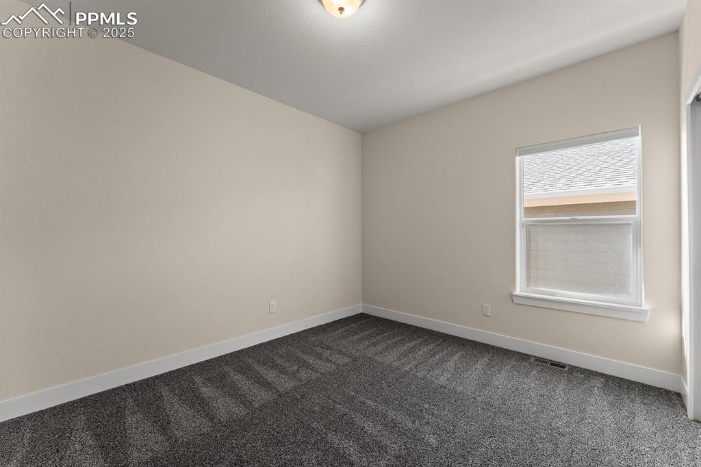 Image 41 of 46: Empty room featuring dark carpet, visible vents, and baseboards