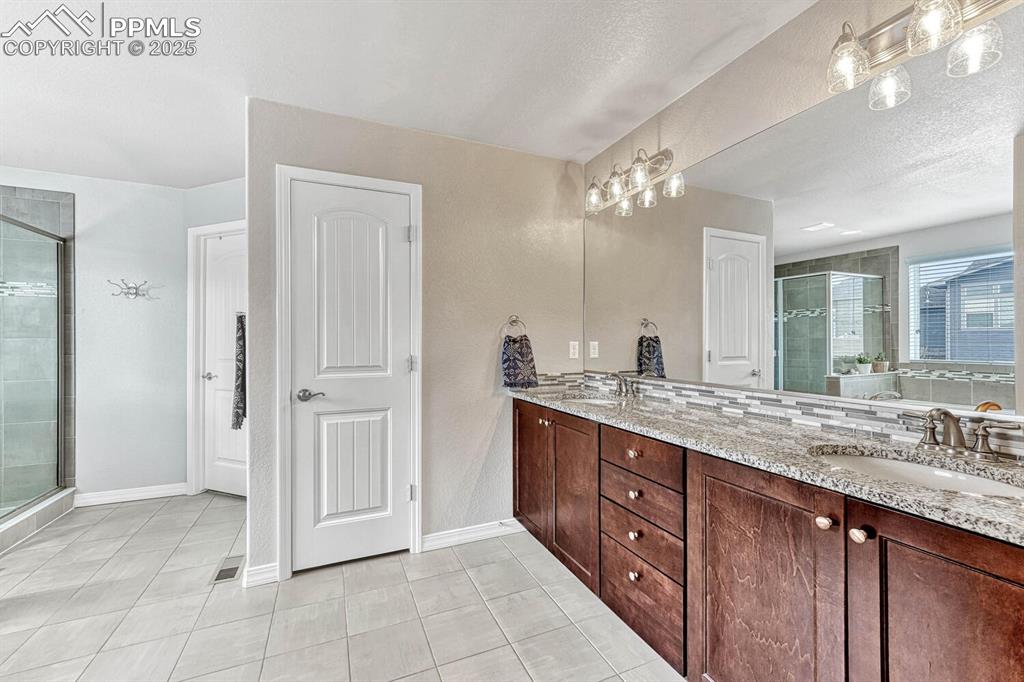 Image 13 of 44: Full bath with a sink, baseboards, a stall shower, and double vanity
