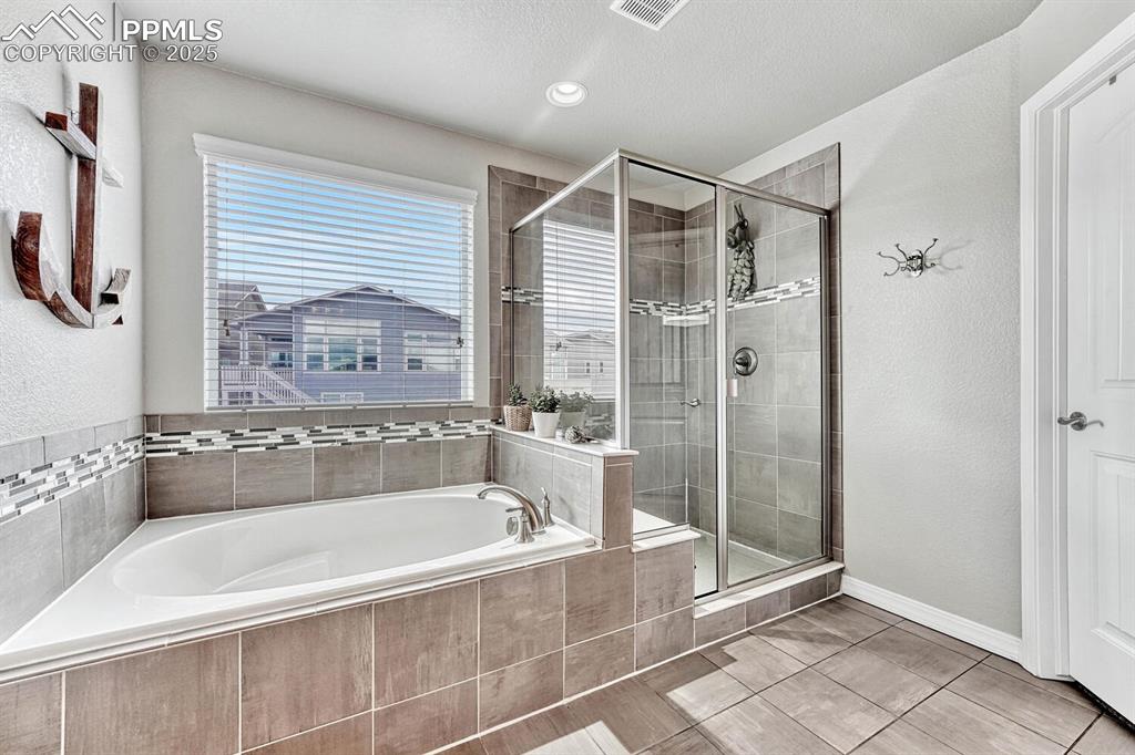 Image 14 of 44: Full bath with a shower stall, a bath, baseboards, and visible vents