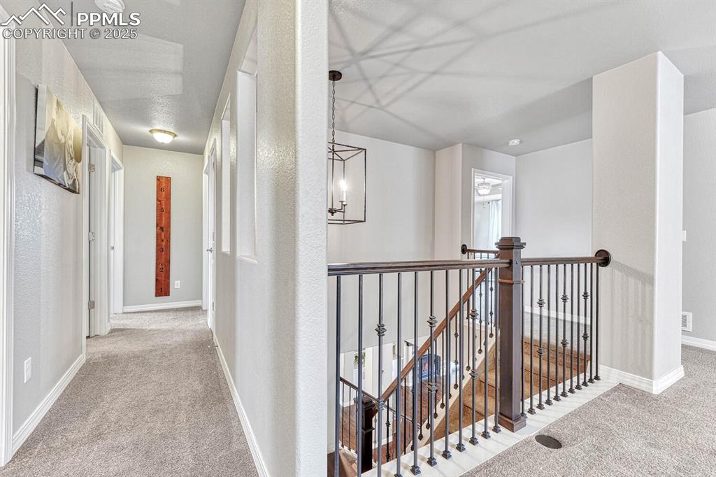 Image 16 of 44: Hallway featuring an upstairs landing, a chandelier, baseboards, and carpet