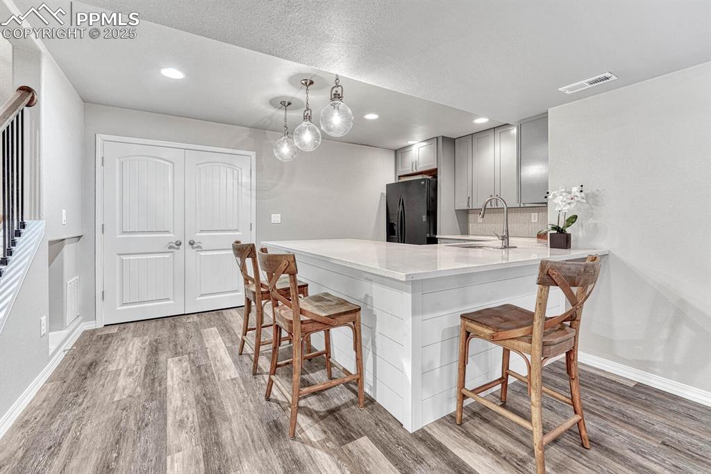 Image 33 of 44: Kitchen featuring a breakfast bar area, visible vents, gray cabinets, a sin
