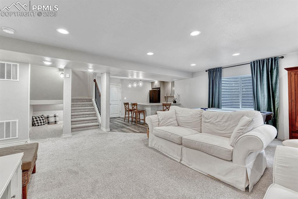 Image 35 of 44: Living area with recessed lighting, visible vents, a bar, and stairway
