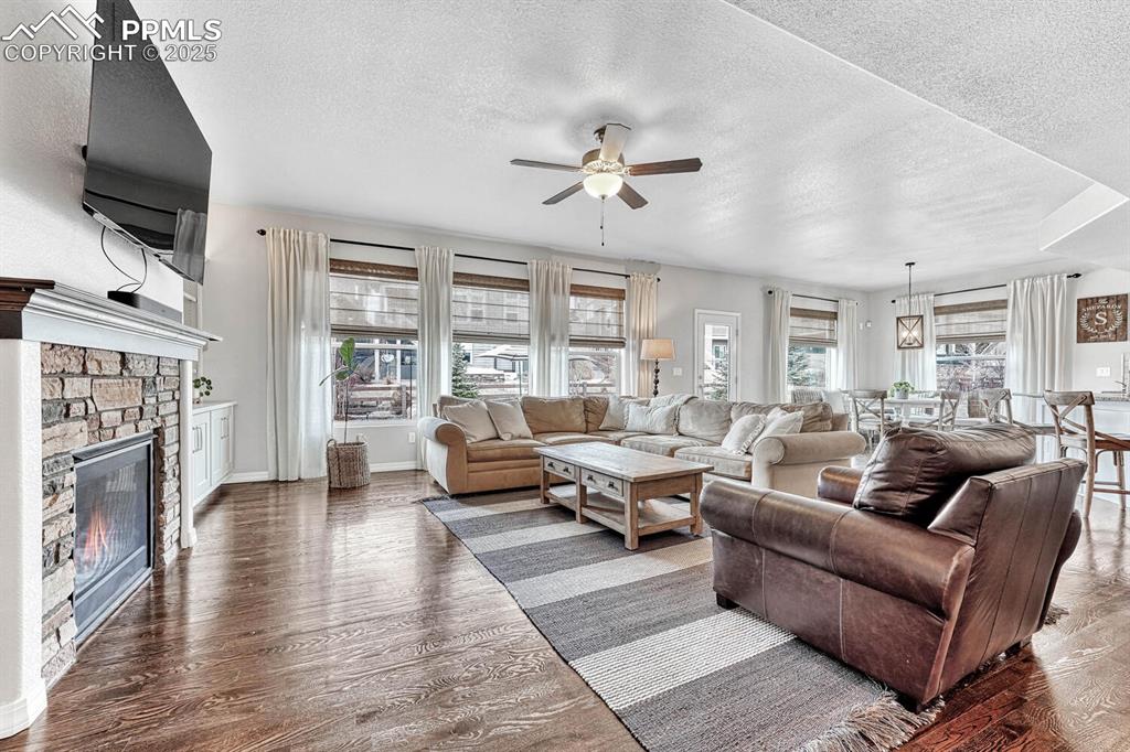 Image 7 of 44: Living area with ceiling fan, a textured ceiling, wood finished floors, and