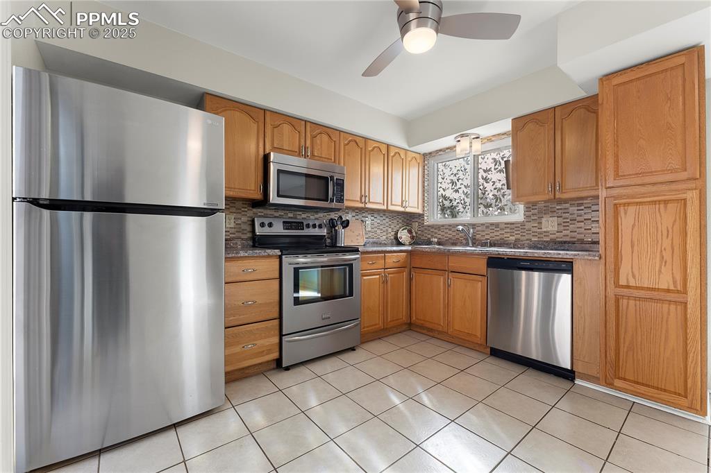 Image 9 of 33: Kitchen with appliances with stainless steel finishes, light tile patterned