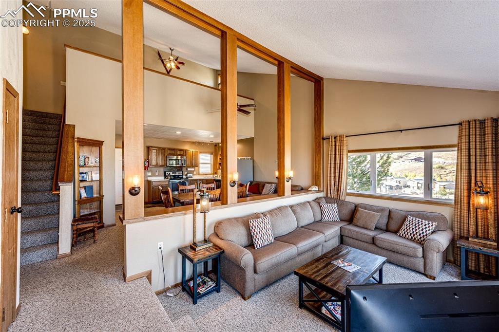Image 13 of 42: Living room with carpet, high vaulted ceiling, stairs, and a textured ceili
