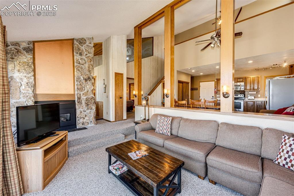Image 17 of 42: Carpeted living room with a high ceiling and a ceiling fan