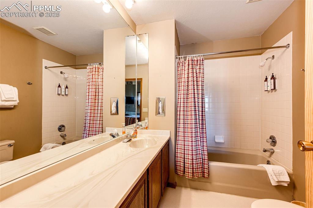 Image 19 of 42: Bathroom with shower / bath combo, vanity, and a textured ceiling