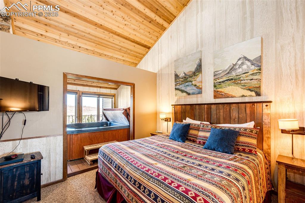 Image 21 of 42: Bedroom featuring wooden walls, light carpet, a wainscoted wall, wooden cei