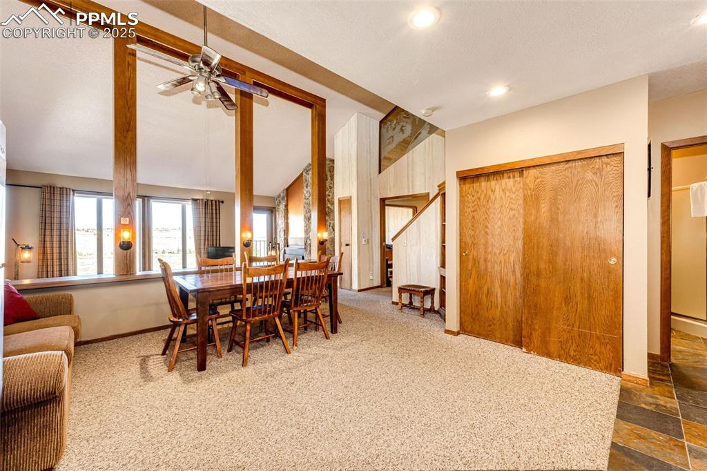 Image 7 of 42: Dining room featuring carpet floors, ceiling fan, high vaulted ceiling, and