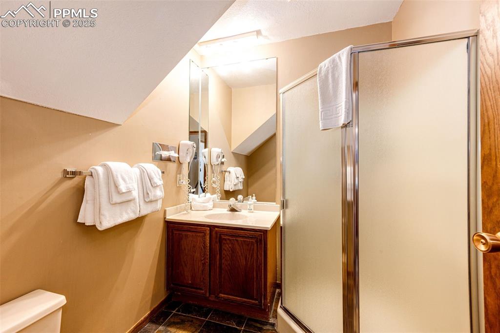 Image 8 of 42: Bathroom featuring vanity, a shower stall, dark tile patterned floors, and
