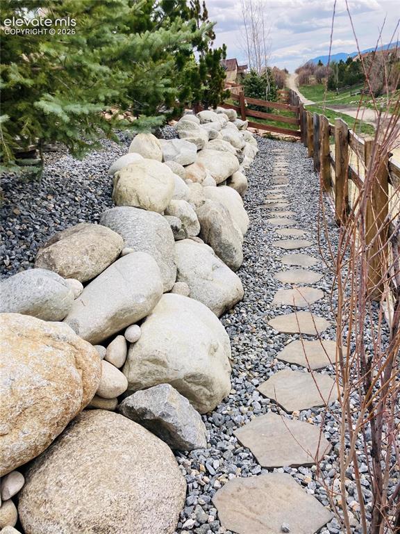 Image 46 of 49: Stone pathway with natural rock retaining wall and gravel ground cover