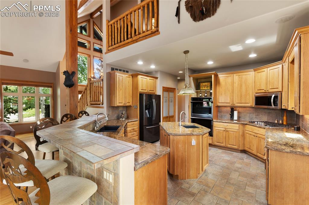 Image 11 of 46: Gourmet kitchen with prep bar in the middle, dual ovens, gas stove and a pa