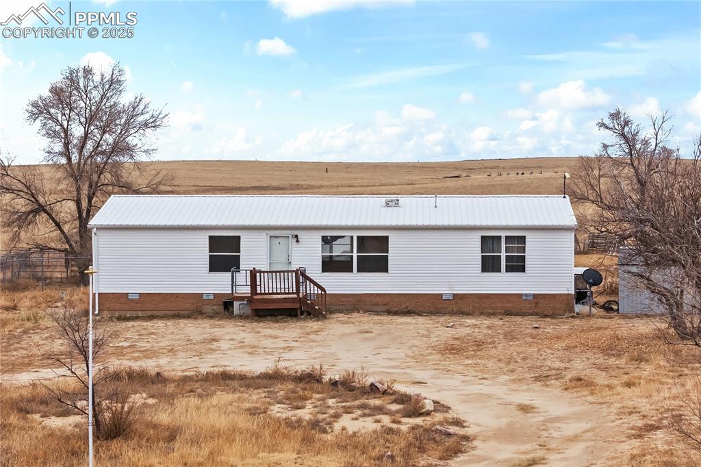 Caption: View of front facade featuring crawl space and a metal roof