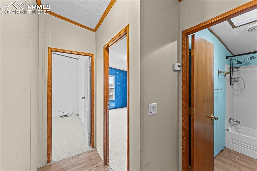 Image 13 of 32: Hallway with a skylight, light wood-type flooring, ornamental molding, and 