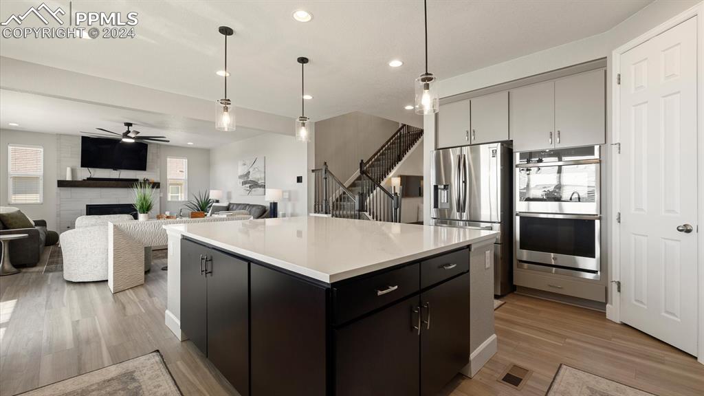 Image 17 of 50: Gourmet Island Kitchen with quatz countertops, pendant lights, and stainles