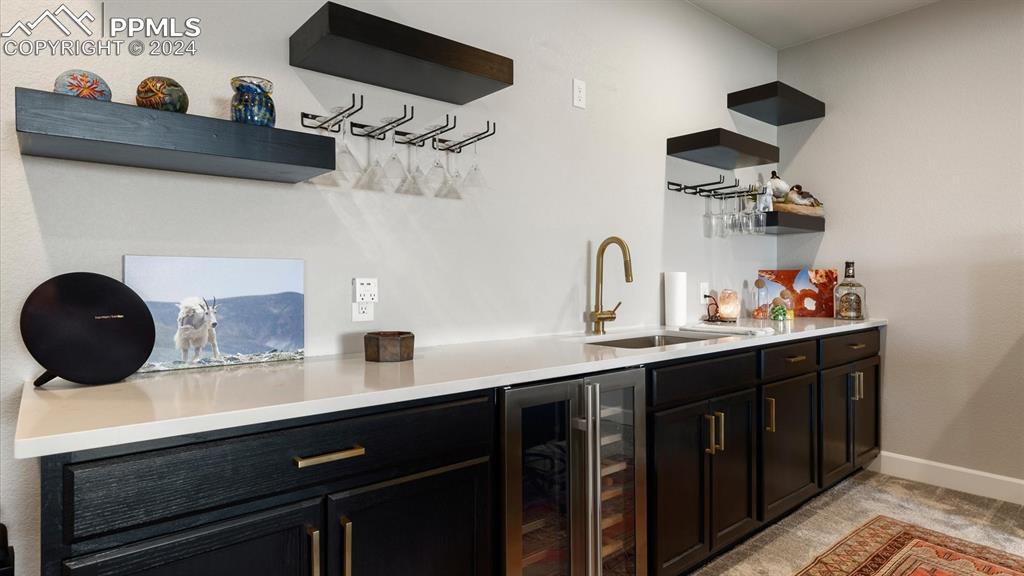Image 42 of 50: Basement wet bar with beverage refrigerator that stays.