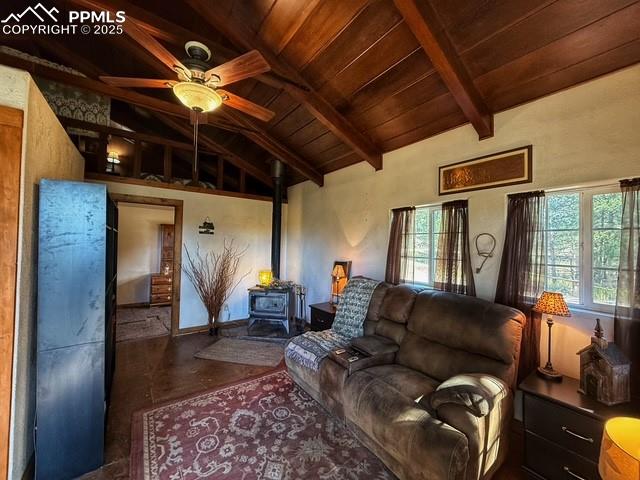 Image 6 of 15: Living area with a wood stove, wooden ceiling, and ceiling fan