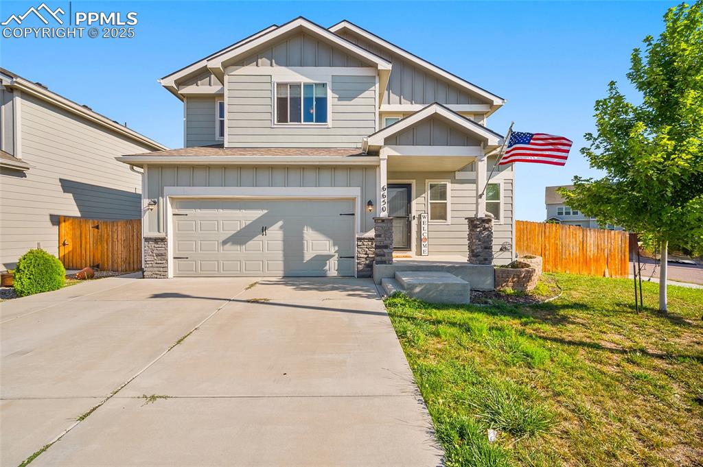 Caption: Craftsman-style house with board and batten siding, stone siding, a garage, and concrete driveway