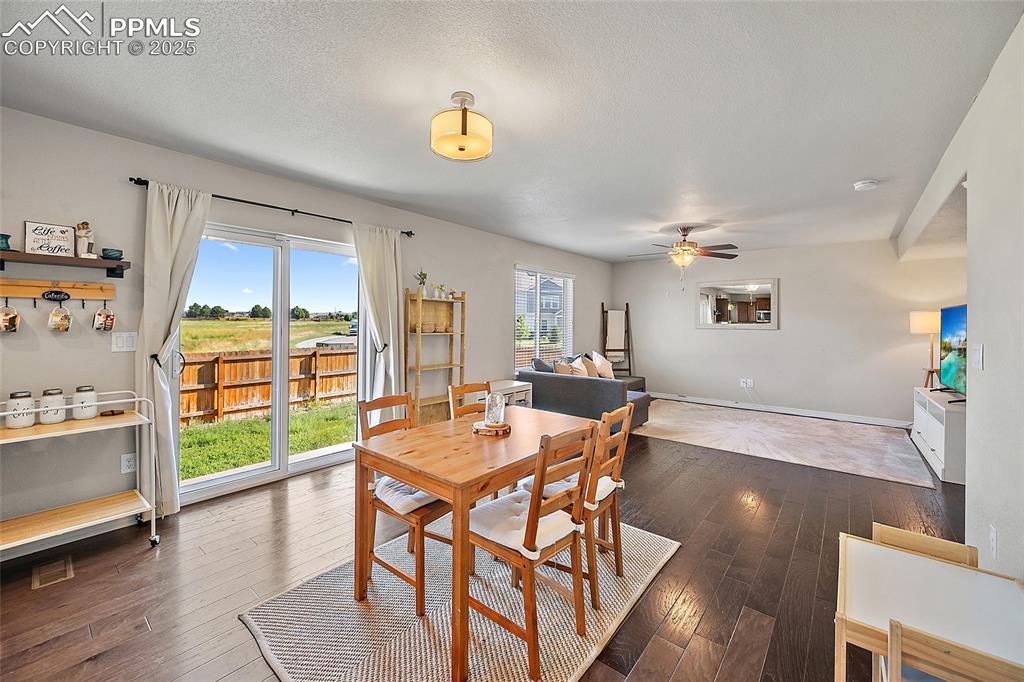 Image 11 of 38: Dining space with dark wood-style flooring, a ceiling fan, and a textured c