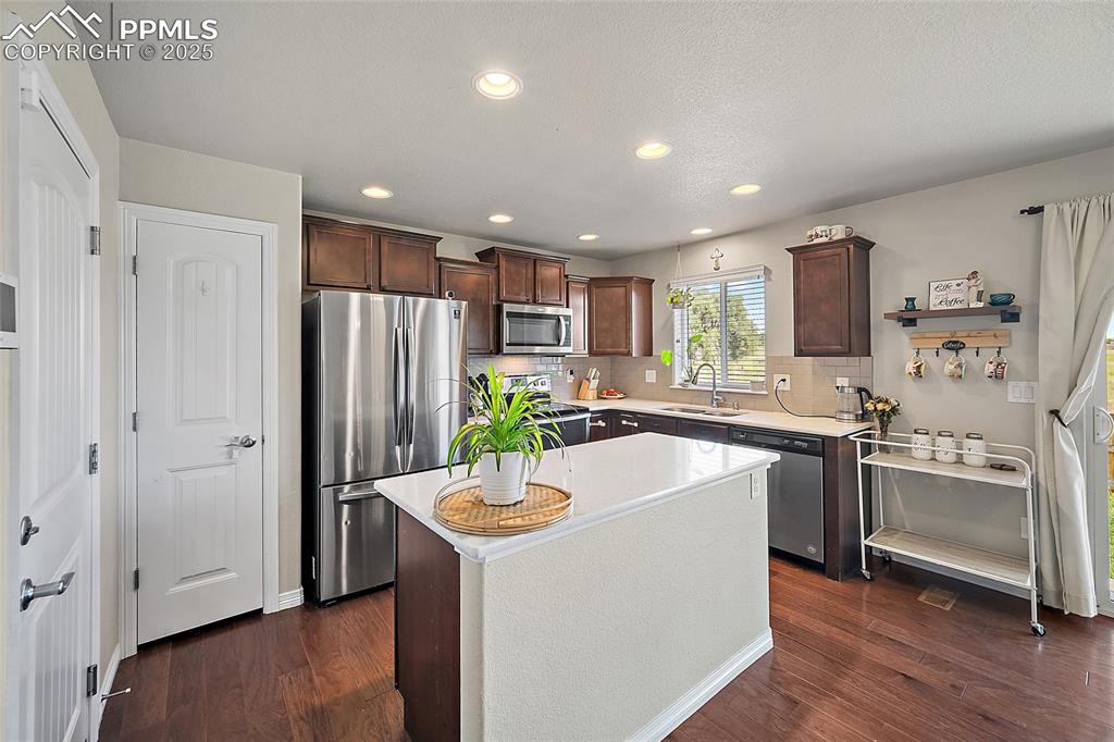 Image 15 of 38: Kitchen featuring dark brown cabinetry, stainless steel appliances, a kitch