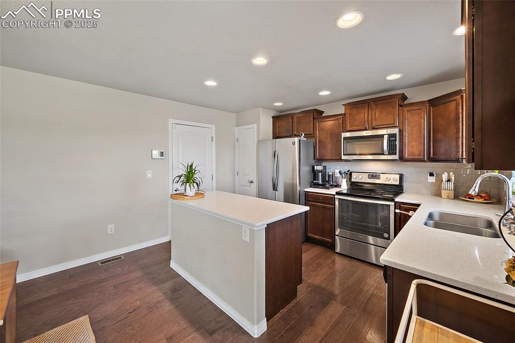 Image 16 of 38: Kitchen with decorative backsplash, appliances with stainless steel finishe