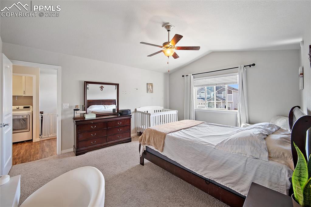 Image 19 of 38: Carpeted bedroom featuring vaulted ceiling, washer / dryer, and a ceiling f
