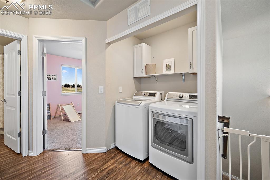 Image 23 of 38: Laundry room featuring dark wood-style flooring, cabinet space, and washer 